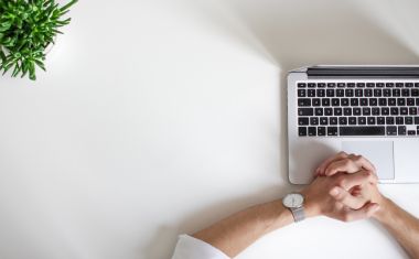 Hands clasped in front of a computer - Photo credit: Nordwood Themes